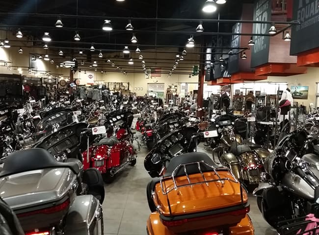 Rows of motorcycles on the large showroom floor of the dealership.